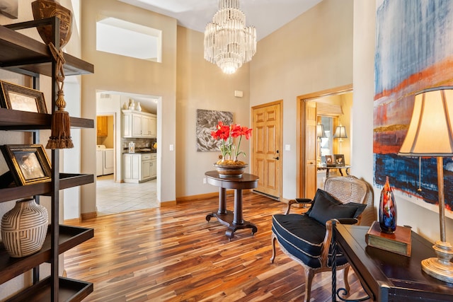 interior space with a notable chandelier, independent washer and dryer, baseboards, and light wood-style floors