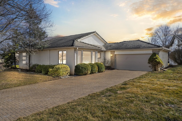 ranch-style house featuring a front lawn, a tiled roof, an attached garage, and driveway