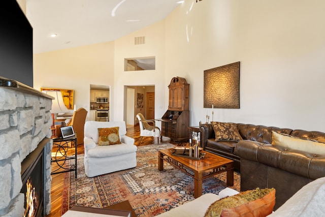 living room with visible vents, recessed lighting, a fireplace, wood finished floors, and high vaulted ceiling