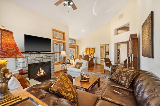 living area featuring visible vents, high vaulted ceiling, a ceiling fan, wood finished floors, and a fireplace