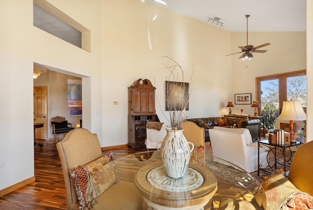 dining area featuring a ceiling fan, a high ceiling, baseboards, and wood finished floors