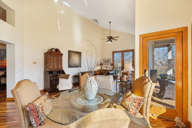 dining space featuring ceiling fan, wood finished floors, and high vaulted ceiling