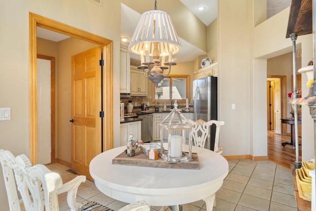 dining space with light tile patterned floors, baseboards, an inviting chandelier, and a towering ceiling