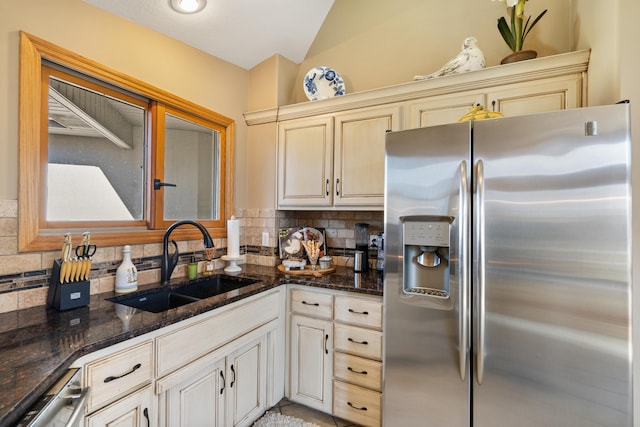 kitchen with a sink, backsplash, stainless steel appliances, dark stone counters, and vaulted ceiling