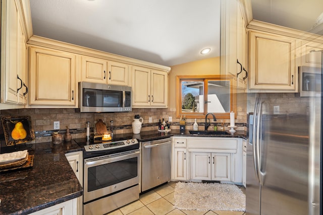 kitchen with light tile patterned floors, lofted ceiling, a sink, appliances with stainless steel finishes, and backsplash