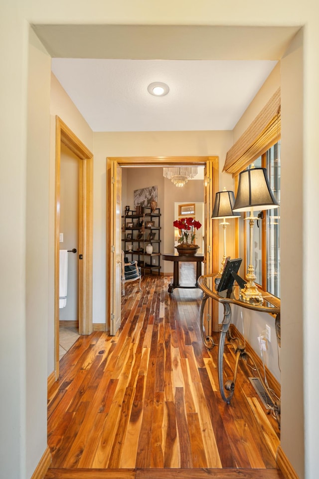 hall with baseboards and wood-type flooring