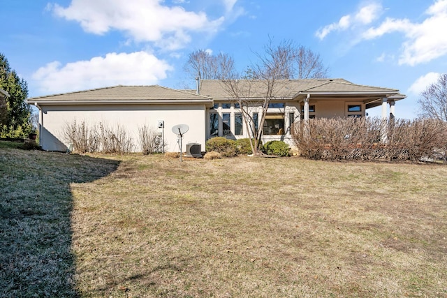 rear view of property featuring a lawn and stucco siding