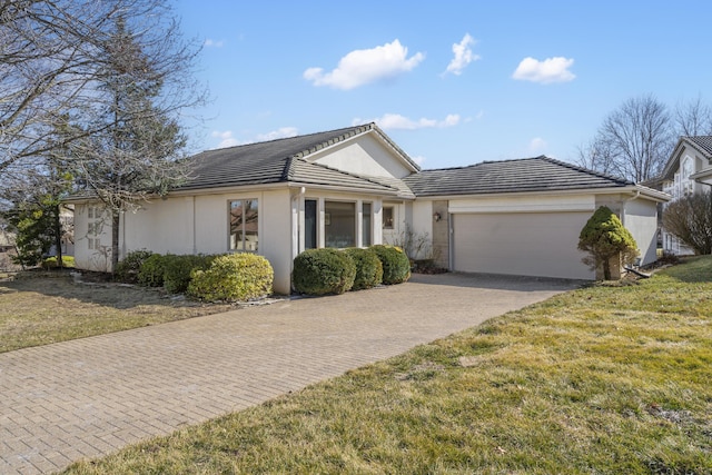 ranch-style home featuring a front yard, decorative driveway, a tile roof, and an attached garage