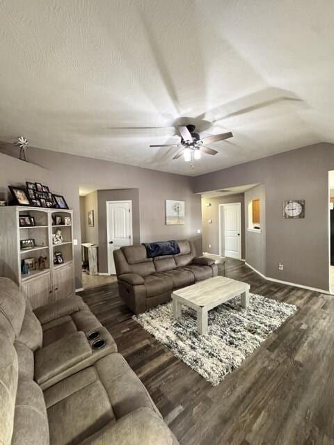 living area with a ceiling fan, a textured ceiling, wood finished floors, baseboards, and vaulted ceiling