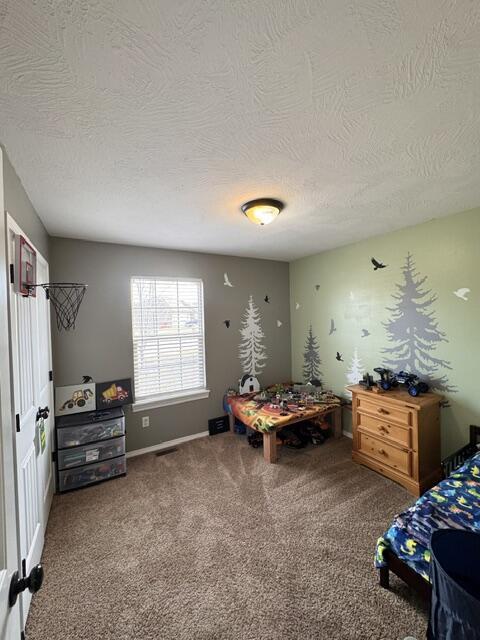 bedroom with carpet, visible vents, and a textured ceiling