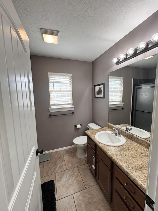 bathroom with vanity, toilet, a healthy amount of sunlight, and a textured ceiling