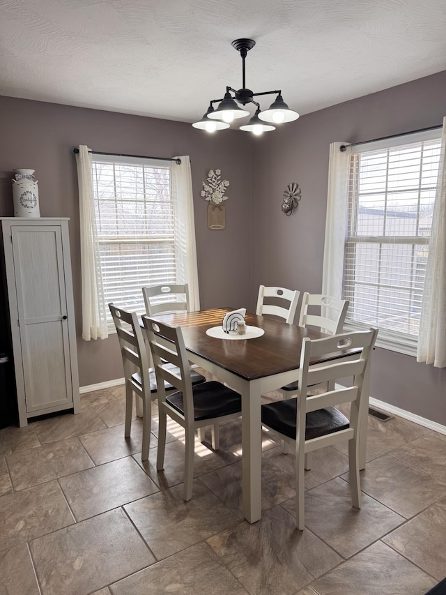 dining area featuring a chandelier, visible vents, and baseboards