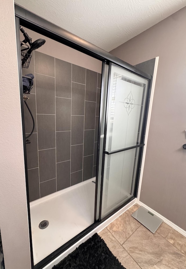 full bath featuring baseboards, a textured ceiling, and a shower stall