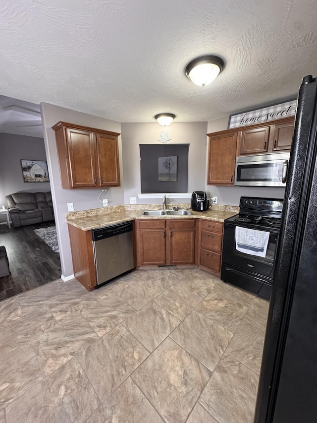 kitchen with black appliances, light stone countertops, brown cabinets, and a sink