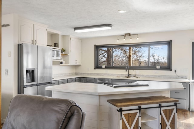 kitchen featuring a sink, open shelves, a textured ceiling, appliances with stainless steel finishes, and light countertops