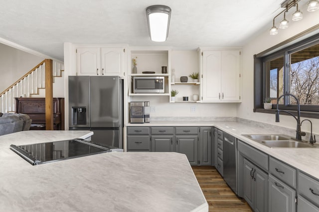 kitchen featuring dark wood-style floors, open shelves, gray cabinets, a sink, and appliances with stainless steel finishes