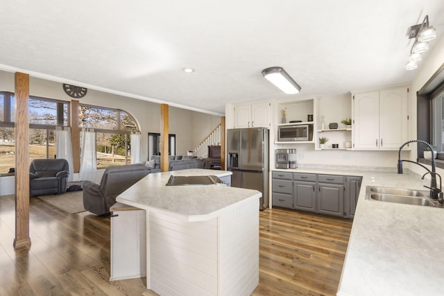 kitchen featuring wood finished floors, open shelves, gray cabinetry, a sink, and appliances with stainless steel finishes