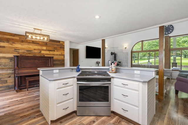 kitchen featuring light wood-type flooring, light countertops, stainless steel range with electric stovetop, white cabinets, and open floor plan