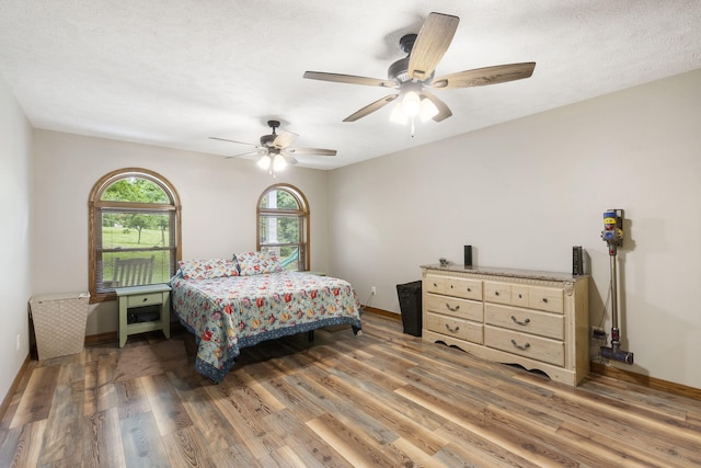 bedroom with ceiling fan, baseboards, and light wood-style floors