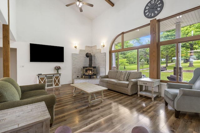 living room with ceiling fan, a wood stove, wood finished floors, and high vaulted ceiling