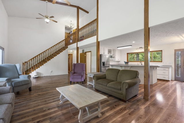 living room featuring dark wood finished floors, an inviting chandelier, stairs, and a towering ceiling