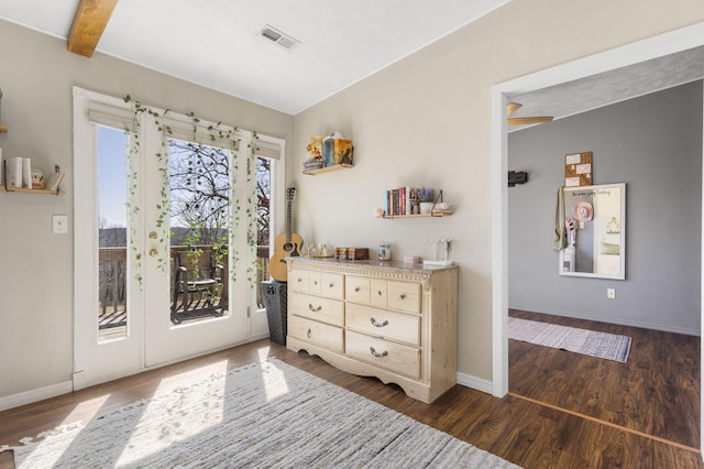 doorway with beam ceiling, visible vents, baseboards, and wood finished floors