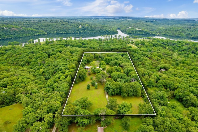 drone / aerial view with a wooded view and a water view