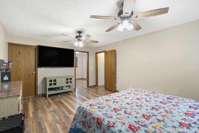 bedroom featuring light wood finished floors, visible vents, ceiling fan, and baseboards