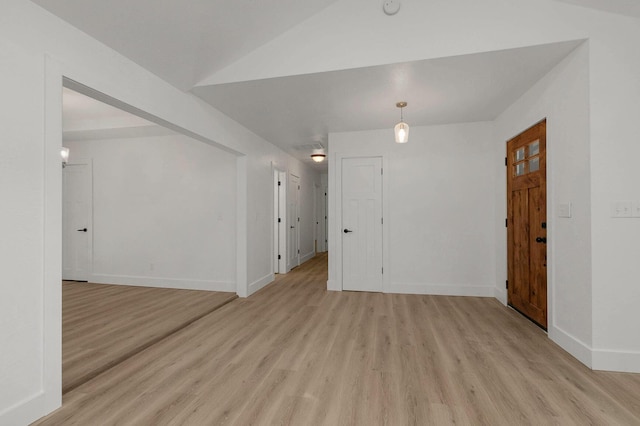 empty room featuring baseboards, light wood-style floors, and lofted ceiling