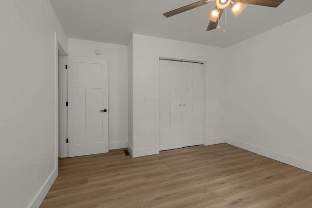 unfurnished bedroom featuring a closet, baseboards, light wood-style floors, and a ceiling fan