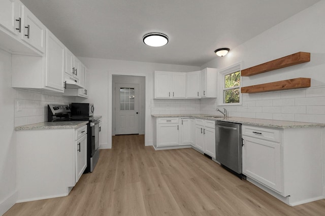 kitchen featuring light wood finished floors, open shelves, a sink, appliances with stainless steel finishes, and under cabinet range hood