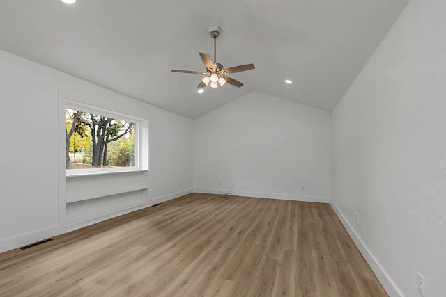 spare room with light wood-type flooring, lofted ceiling, and baseboards