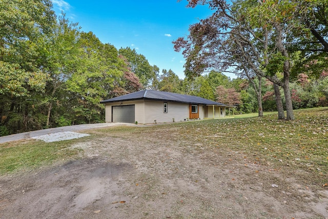 view of home's exterior with a garage, dirt driveway, and metal roof