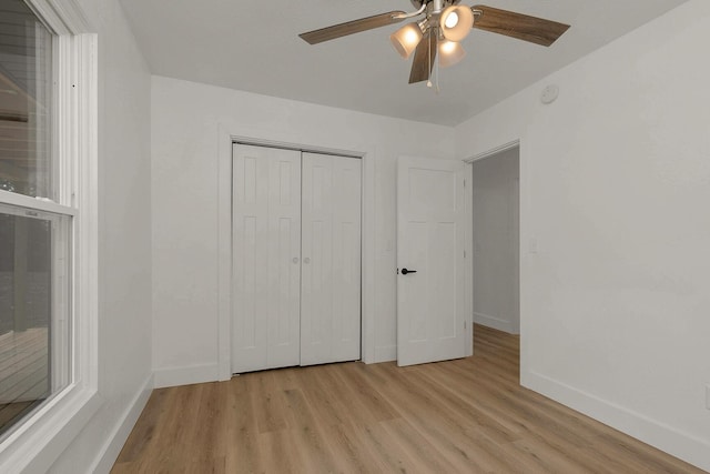 unfurnished bedroom featuring light wood-style flooring, a ceiling fan, baseboards, and a closet