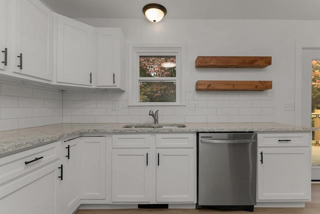 kitchen with a sink, backsplash, stainless steel dishwasher, white cabinets, and light stone countertops