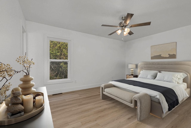 bedroom with light wood-type flooring, baseboards, visible vents, and a ceiling fan