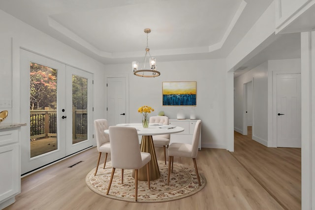 dining space featuring a raised ceiling, french doors, light wood-type flooring, and visible vents