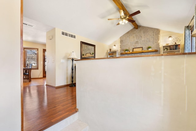 corridor featuring lofted ceiling with beams, wood finished floors, visible vents, and baseboards