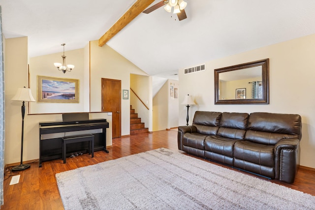 living room featuring visible vents, ceiling fan with notable chandelier, wood finished floors, stairs, and vaulted ceiling with beams