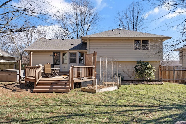 rear view of property with a hot tub, fence, a lawn, a garden, and a gate