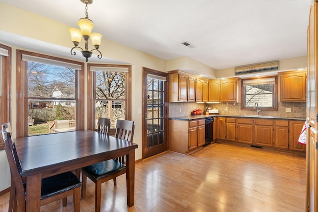 dining space featuring light wood finished floors, a chandelier, and visible vents