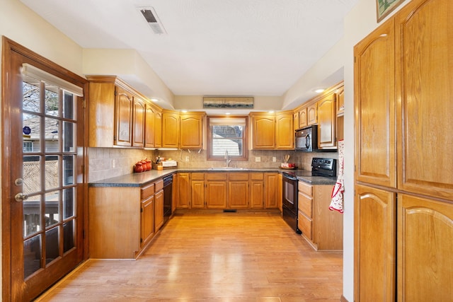 kitchen with black appliances, tasteful backsplash, visible vents, and light wood-type flooring