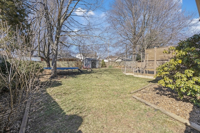 view of yard featuring a storage shed, an outbuilding, a trampoline, and fence