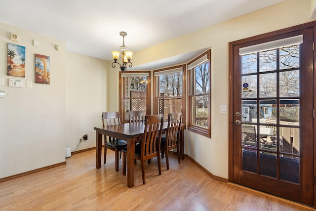 dining area featuring light wood-type flooring, baseboards, and a notable chandelier