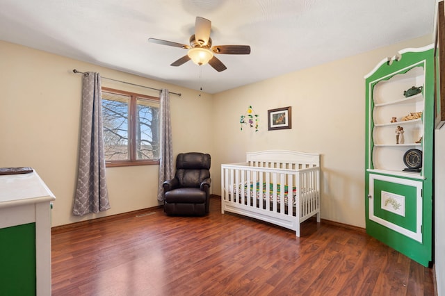 bedroom featuring ceiling fan, visible vents, a nursery area, and wood finished floors