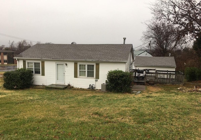 view of front facade featuring a shingled roof, a front lawn, central AC unit, and a wooden deck