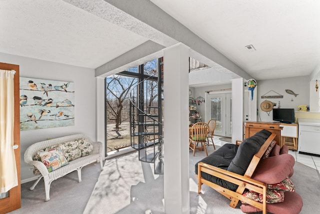 sitting room with carpet, visible vents, and a textured ceiling