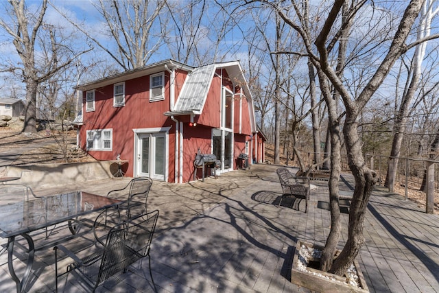 back of house featuring a barn, outdoor dining area, an outbuilding, and a gambrel roof