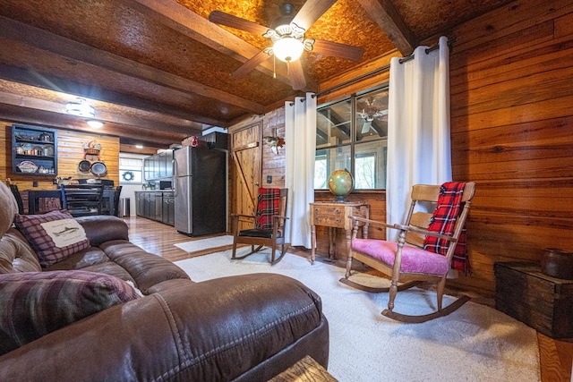 living room featuring beam ceiling, wooden walls, and a wealth of natural light