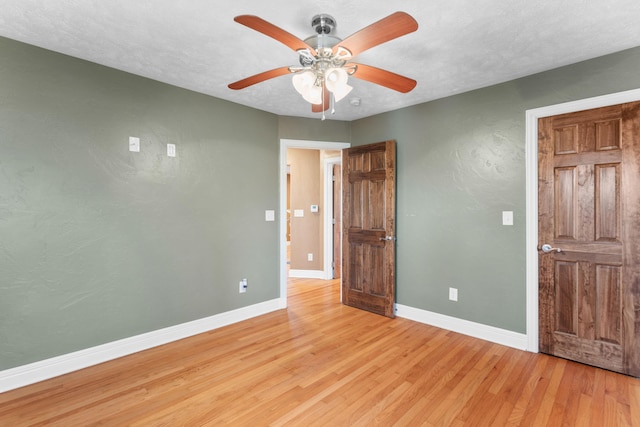 unfurnished bedroom with ceiling fan, baseboards, a textured ceiling, and light wood-style flooring